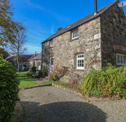 A stone house with trees and garden area at Carthouse Cottage in Clarbeston Road