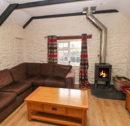A living room with a sofa and stove at Knap Cottage in Clarbeston Road