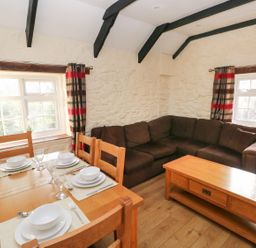 A living room with a dining table set and a sofa at Knap Cottage in Clarbeston Road