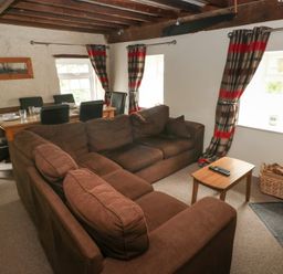 A living room with a sofa and dining area at Shippen Cottage in Clarbeston Road