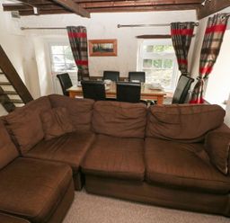 A living room with a sofa and dining table at Shippen Cottage in Clarbeston Road