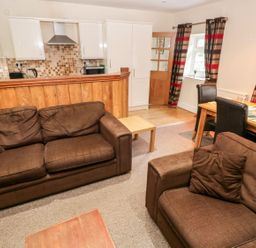 A living room with sofas and a dining area at Lake Cottage in Clarbeston Road