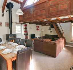 A living room with a fireplace and dining table at Granary Cottage in Clarbeston Road