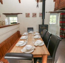 A dining room with a large table set for meals at Granary Cottage in Clarbeston Road