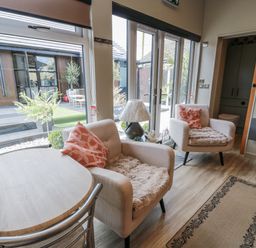 A living room with a table and chairs next to large windows at Cabin At The Brig Annan