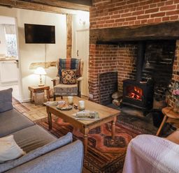 A living room with a sofa and fireplace at The Old Post Box in Halesworth