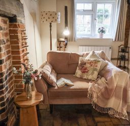 A living room with a sofa and fireplace at The Old Post Box in Halesworth