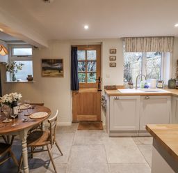 A kitchen with a dining table and sink at The Old Post Box in Halesworth