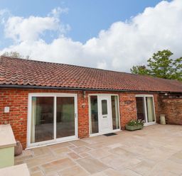 An exterior view of a brick building with a patio at The Owl Barn Cottage