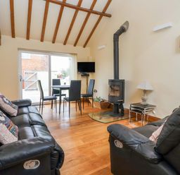 A living room with a sofa and dining area at The Owl Barn Cottage