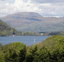 A view of a lake with mountains and a sailboat at Feather Hill Lodge in Windermere