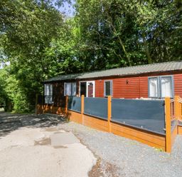 A cabin with a deck surrounded by trees at Feather Hill Lodge White Cross Bay, Skiptory Howe 38