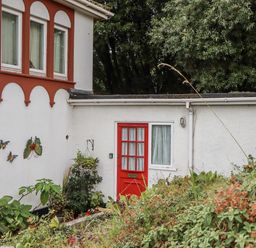 An outdoor area with a red door and decorative butterflies at Mayflower View in Dawlish