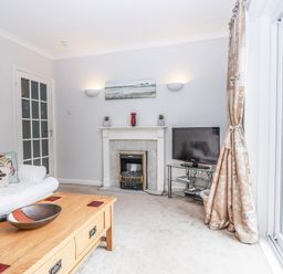 A living room with a sofa, coffee table, and television at Mayflower View in Dawlish