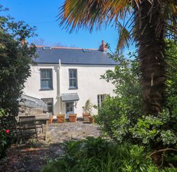 A garden with a dining table and palm tree at Pedn Brose Near Mousehole