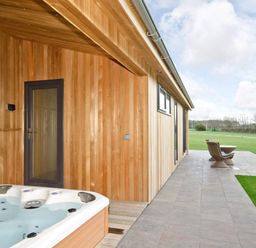 An outdoor area with a hot tub and seating at Brayton in Aspatria