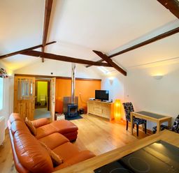 A living room with a sofa, television, and wooden furniture at Upper Stable - The Stables Apartments at Meadfoot Bay, Torquay