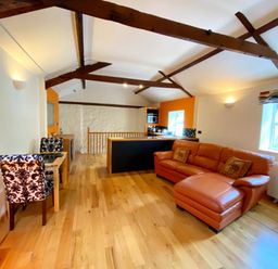 A living room with a sofa and dining area at Upper Stable - The Stables Apartments at Meadfoot Bay, Torquay