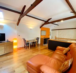 A living room with a television and dining area at Upper Stable - The Stables Apartments at Meadfoot Bay, Torquay