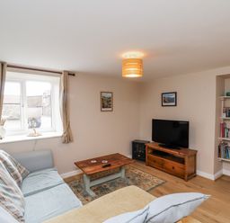 A living room with a sofa and television at Starlight Cottage in 