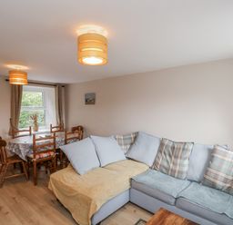A living room with a sofa and dining table at Starlight Cottage