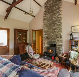 A living room with a stone fireplace and wooden furniture at Tyn Y Fron in Brynherbert near Llanrhystud