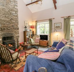 A living room with a fireplace and sofa at Tyn Y Fron in Brynherbert near Llanrhystud