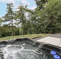 A hot tub and seating area in an outdoor space at Oak View in Rhayader