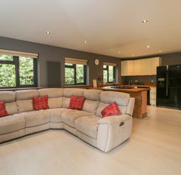A living room with a sofa and kitchen area at Willow Cottage in Whiteparish