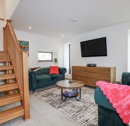 A living room with a staircase, couch and coffee table at Barn 2