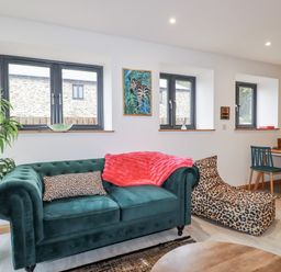 A living room with a green sofa and a dining table at Barn 2 