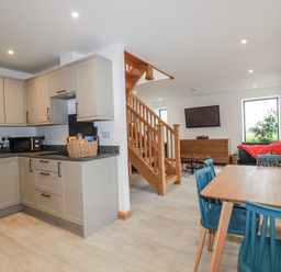 A kitchen and dining area with a staircase and living space at Barn 2 
