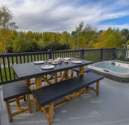 A table and hot tub on a deck at Lakewood Retreat in Woodhall Spa