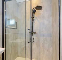 A shower with glass partition and sink in a bathroom at The Woodnewton in Wansford