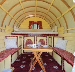 A main room with a table and seating at The Bowtop Gypsy Caravan in Eye