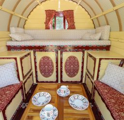 A living room with cushions and a table at The Bowtop Gypsy Caravan in Eye