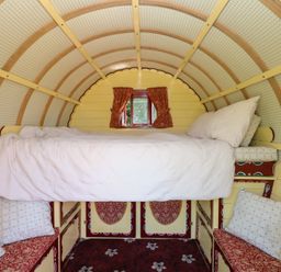 A bedroom with a bed and cushions at The Bowtop Gypsy Caravan in Eye