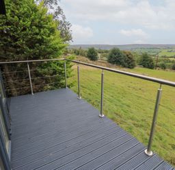 An outdoor deck area with railing and view of hills at John's Folly