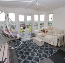 A conservatory with a hanging chair and couch at John's Folly