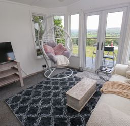 A living room with a hanging chair and television at John's Folly