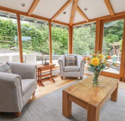 A conservatory with armchairs and a table at Bobbin Mill Cottage in Ulverston