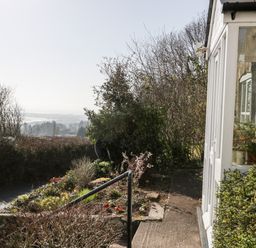 A garden with flowering plants and bushes beside a white building with windows at Gordons View Pleasant Stile near Gloucester