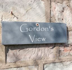 A rectangular stone sign with Gordons View written on it attached to a stone wall at Gordons View Pleasant Stile near Gloucester