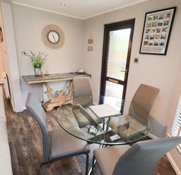 A dining room with a glass table and chairs at Costapacket Grasmere 12, White Cross Bay near Windermere