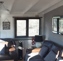 a living room with a window, a lamp, and a decorative sign at Hafan y Mor Haven - Holiday Accommodation 10104 in Pwllheli