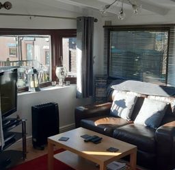 a living room featuring a brown sofa, coffee table, and window with blinds at Hafan y Mor Haven - Holiday Accommodation 10104, Pwllheli