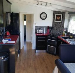 a kitchen with black cabinets and red countertops at Hafan y Mor Haven - Holiday Accommodation 10104 in Pwllheli