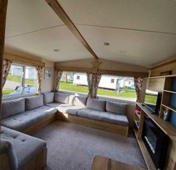 a living room with a sectional sofa and windows at Hafan y Mor Haven - Holiday Accommodation 12637 Pwllheli