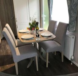 a dining table set with plates and a bottle on display at Kelling Heath Holiday Park - Holiday Accommodation 13133, Holt