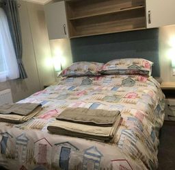 a bedroom with a double bed covered in a patterned quilt at Kelling Heath Holiday Park - Holiday Accommodation 13133, Holt